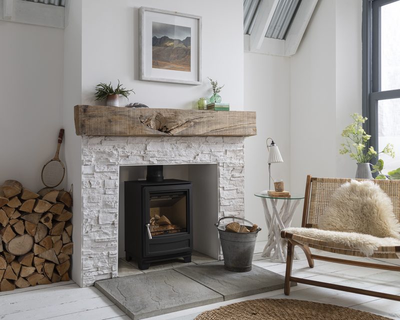 Arada Ecoburn 5 multi-fuel stove in a stone fireplace with wooden beam mantel